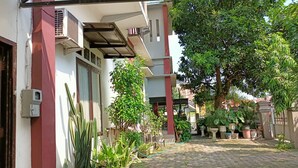 A courtyard with potted plants, a metal structure, and a large tree.