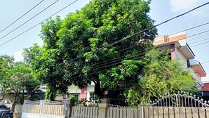 A residential area with a gated entrance, a tree-lined street, and a multi-story building in the background.