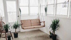 A room with a wooden swing chair, a chair, and several potted plants. - Voted the Top short-term rental in BISMARCK!! (Bismarck)