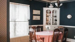 A dining room with a round table, six wooden chairs, a white cabinet with glass doors, and a radiator. - Voted the Top short-term rental in BISMARCK!! (Bismarck)