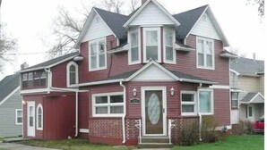 A two-story house with a prominent bay window, a front porch, and a brick foundation. - Voted the Top short-term rental in BISMARCK!! (Bismarck)
