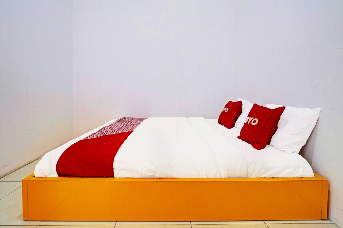 A bed with a white and red bedspread, two red pillows with white text, and an orange bed frame.