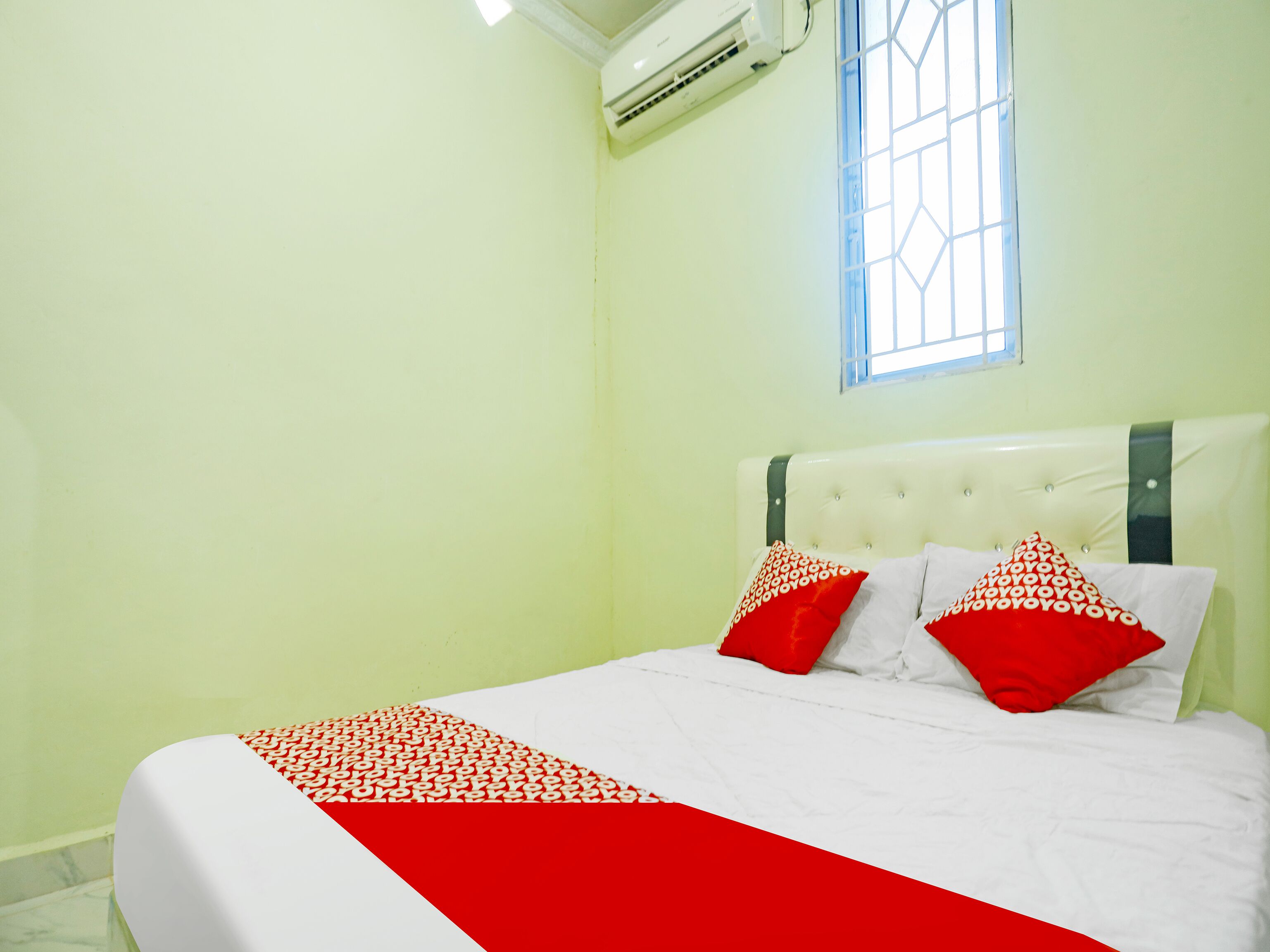A bedroom with a bed, a window, and an air conditioning unit.