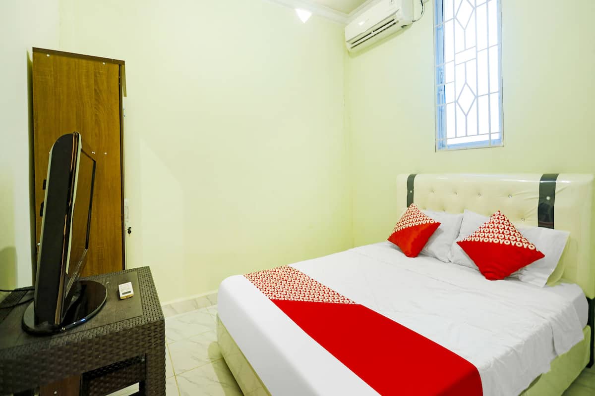 A hotel room with a bed, a wooden door, a window, and an air conditioning unit.