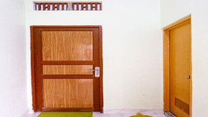 A wooden door with a metal handle, a green mat at the entrance, and a decorative wooden piece above it. - OYO 91314 Zein House (Batam)
