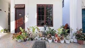 A building with a tiled entrance, a door, a window, and multiple potted plants. - OYO 91314 Zein House (Batam)