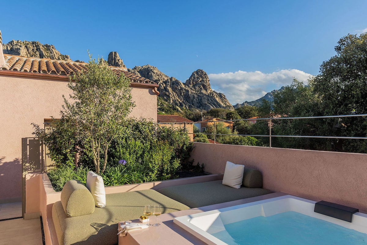 Eine Dachterrasse mit Pool, Sitzgelegenheiten und Blick auf felsige Berge.