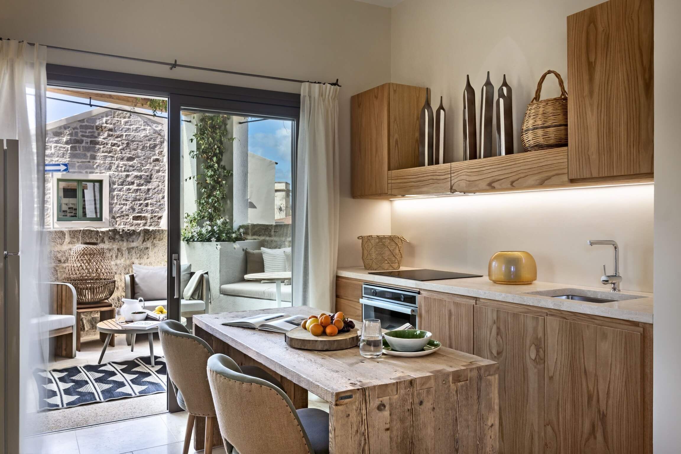 A modern kitchen with wooden cabinets, a built-in oven, and a dining area with a table and chairs.
