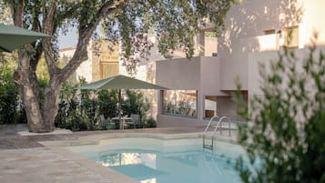 En sÀsongsöppen utomhuspool, parasoller och solstolar