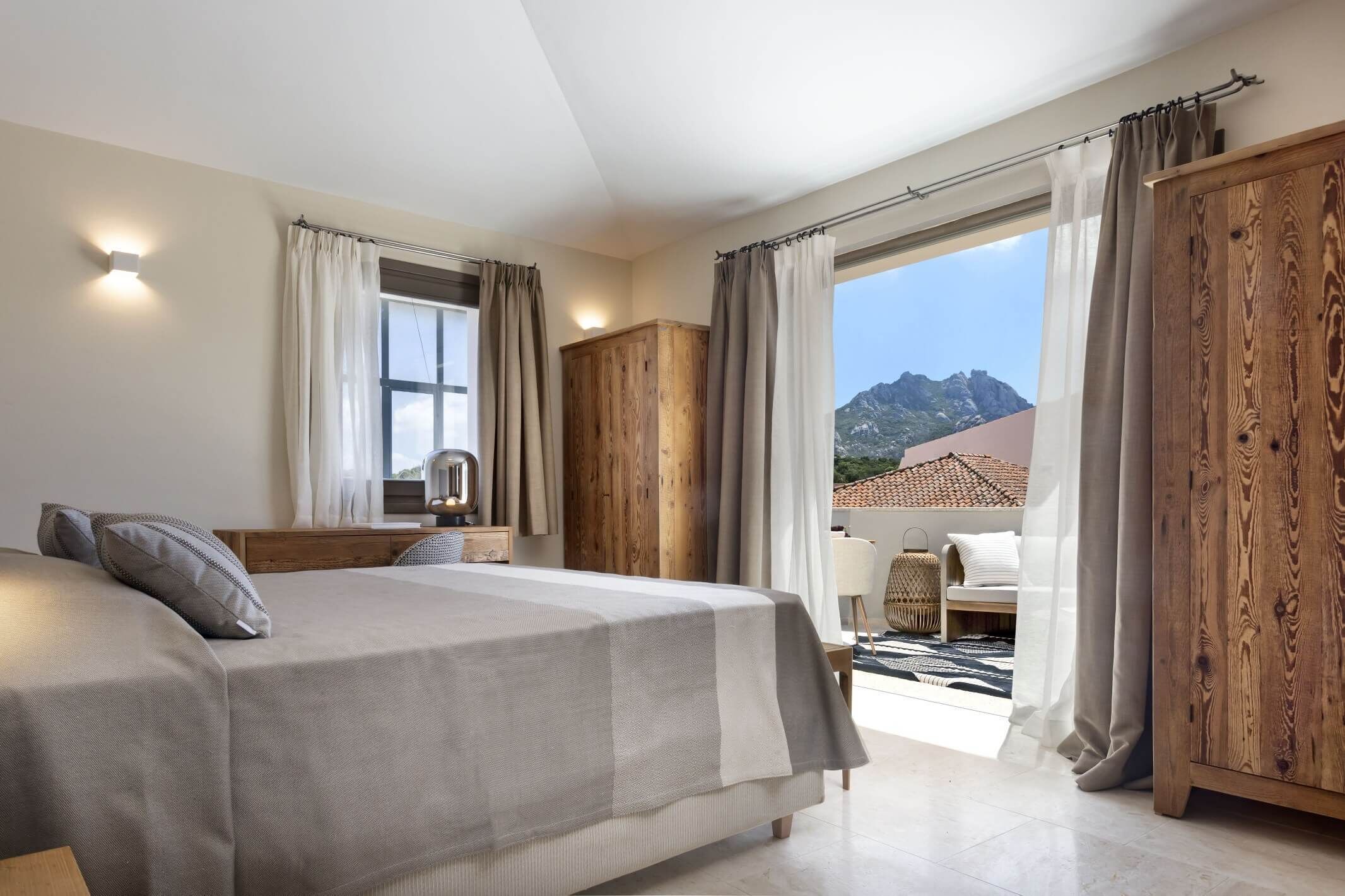 Una camera da letto con un letto, un armadio in legno e vista sulle montagne.