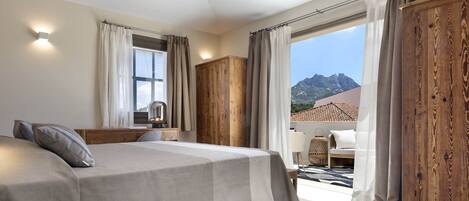 Une chambre à coucher avec un lit, une armoire en bois et une vue sur les montagnes.