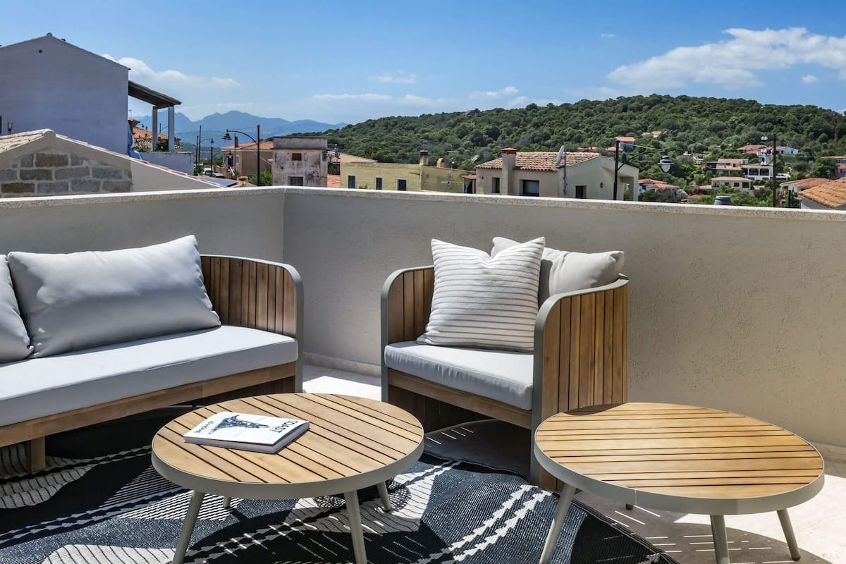 Ein Balkon mit zwei Sofas und zwei runden Tischen, einer mit einem Buch darauf.