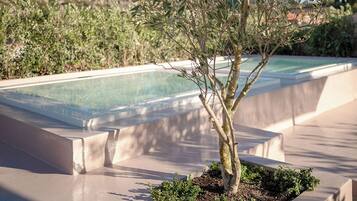 En sÀsongsöppen utomhuspool, parasoller och solstolar