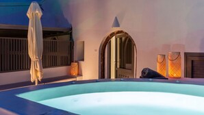 Un jacuzzi con vista a una puerta de madera y una lámpara montada en la pared.