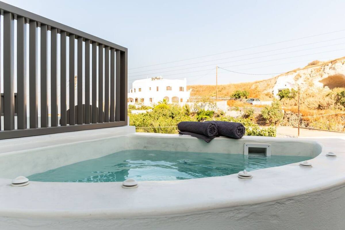 Un jacuzzi con una toalla, una valla de metal y un edificio al fondo.