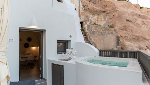 Un edificio moderno blanco con un jacuzzi, una escalera que lleva a un dormitorio y vistas de terreno rocoso.
