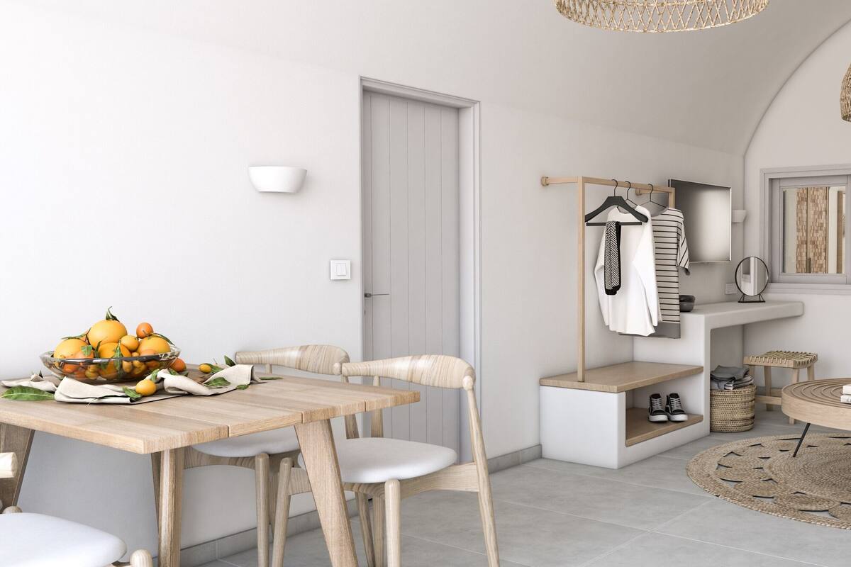 Una habitación moderna y bien iluminada con comedor, perchero, una mesa redonda de centro y un espejo grande que refleja la habitación.