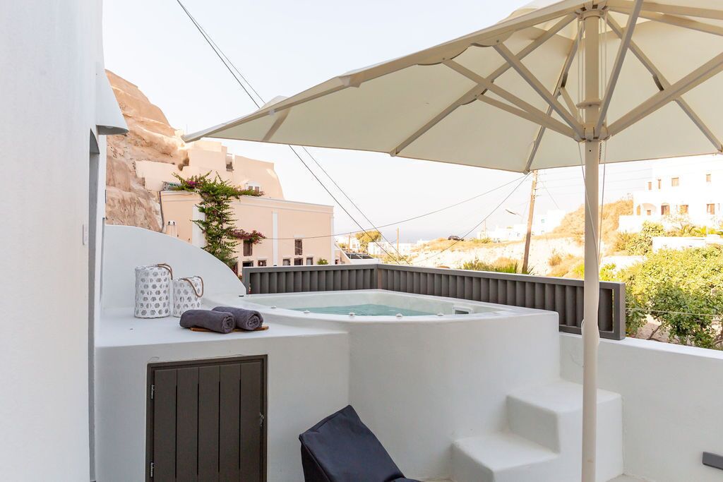 Une terrasse sur le toit avec un jacuzzi, des sièges d’extérieur et un grand parasol.