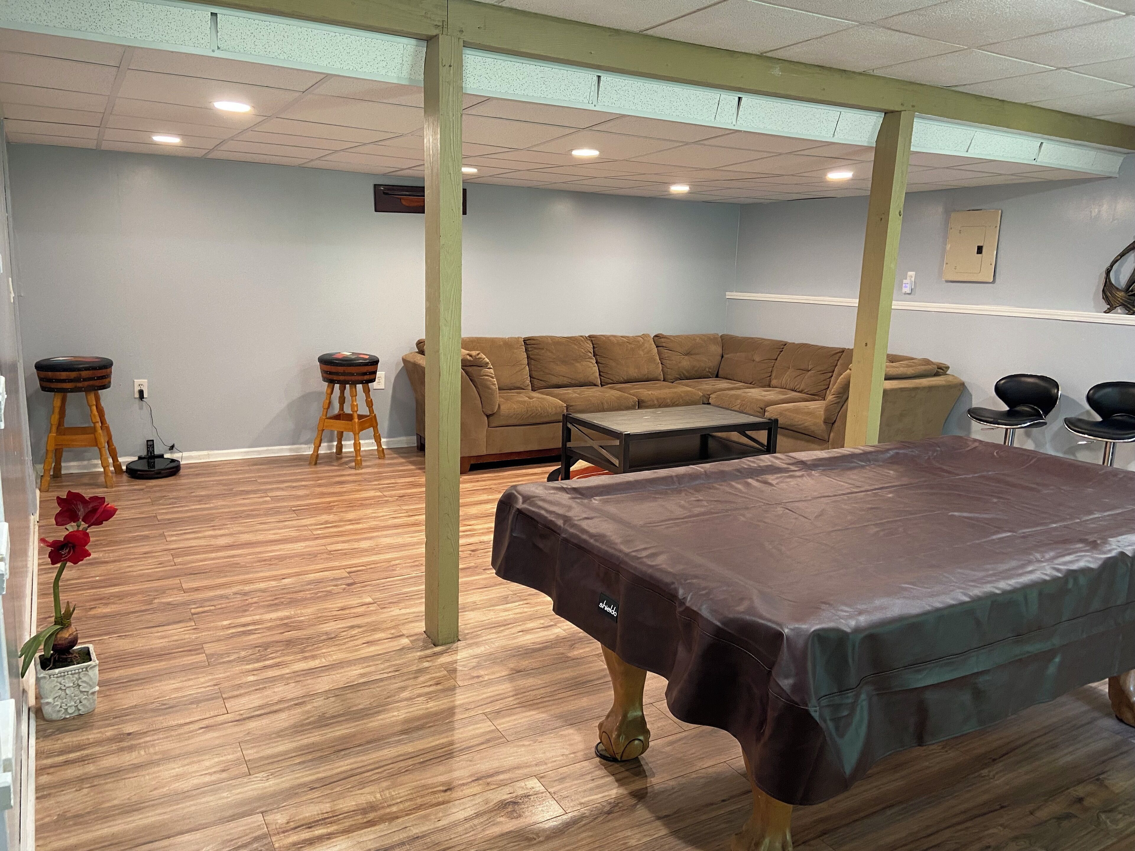 A room with a wooden floor, a brown sofa, a coffee table, and a massage table.