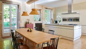 A modern kitchen with a wooden dining table, pendant lights, and a built-in oven.