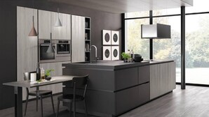 A modern kitchen with a central island, pendant lights, and a large window providing a view of the outdoors.