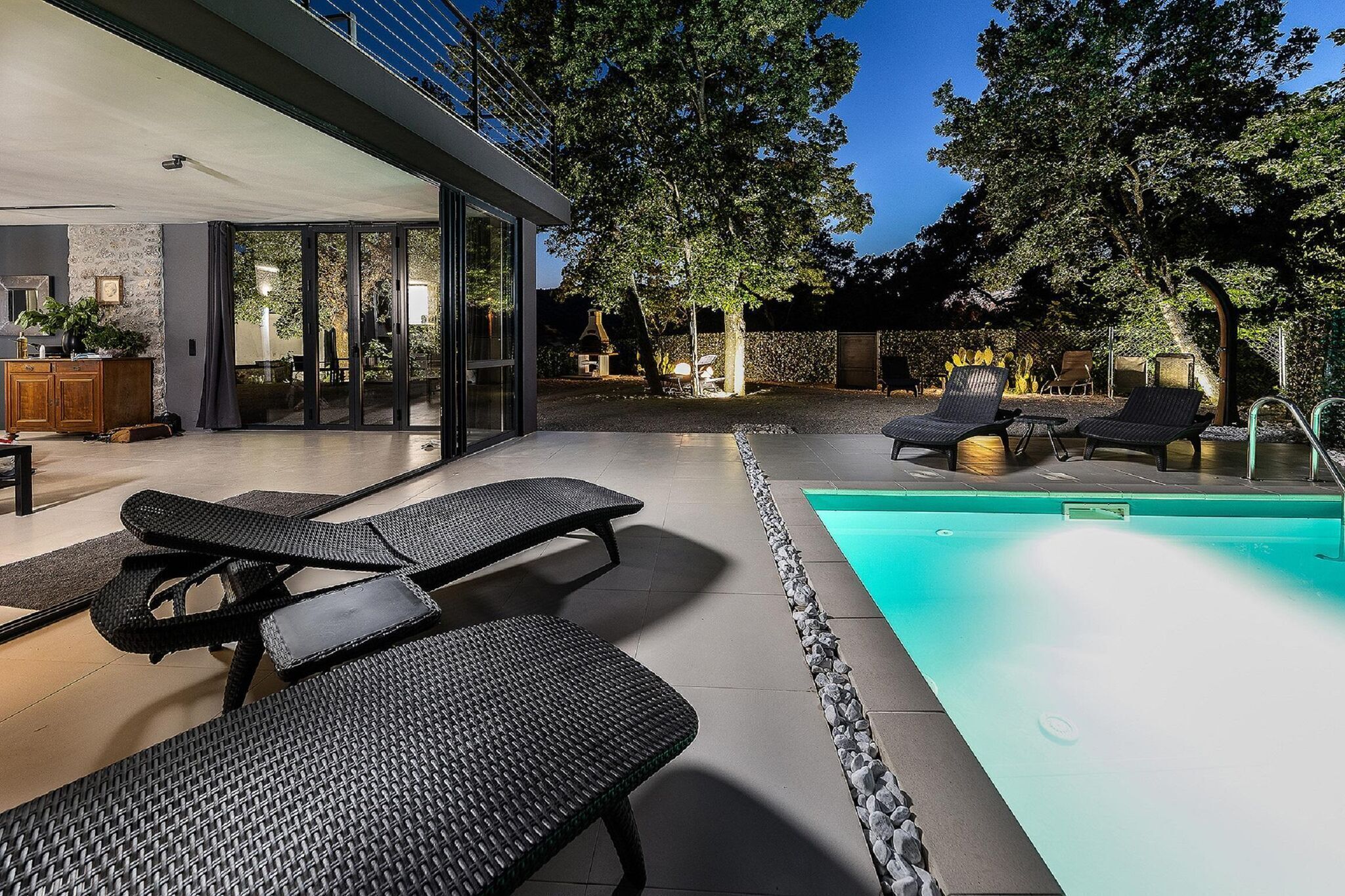 Un espace piscine extérieur moderne, doté de chaises longues et d’une piscine à l’eau d’un bleu cristallin.
