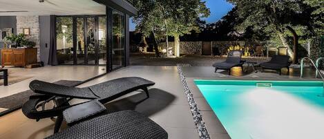 Un espace piscine extérieur moderne, doté de chaises longues et d’une piscine à l’eau d’un bleu cristallin.