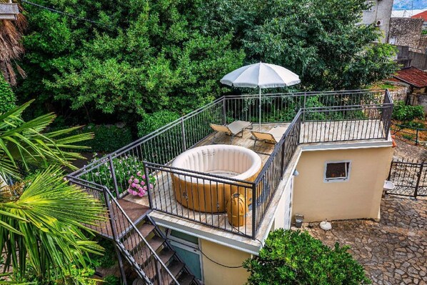 Una terraza en la azotea con jacuzzi, sillones de descanso y una sombrilla.