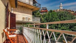 A balcony with a white railing, wooden chairs, and a small table.