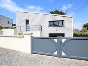 Un immeuble moderne à deux étages, doté d’une entrée sécurisée par un portail, d’un petit balcon et d’une fenêtre bien visible.