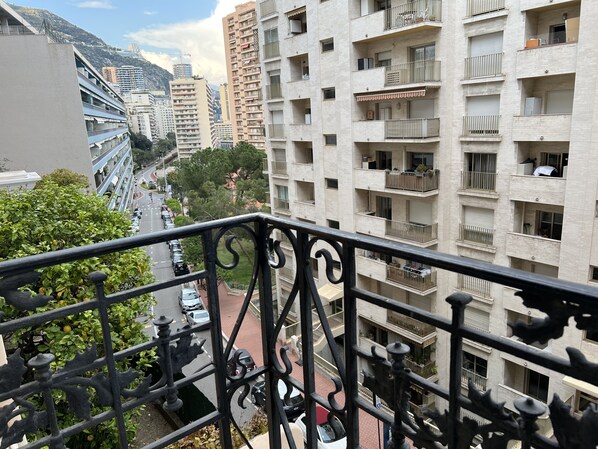 Un edificio residencial de varios pisos con balcones, vista a la calle y montañas al fondo.