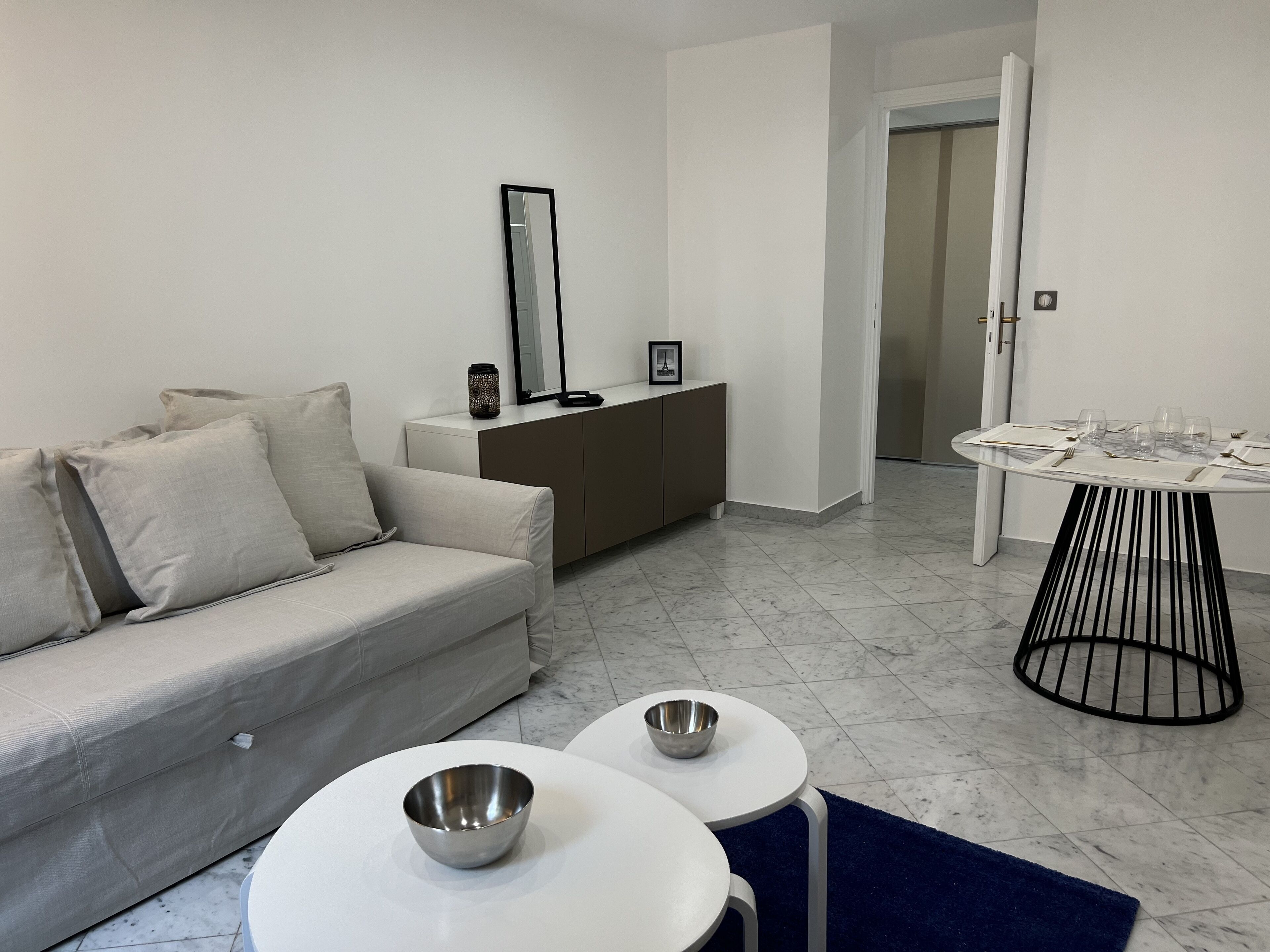 Un salon moderne avec un canapé, une table à manger dressée pour deux personnes et une petite table d’appoint.