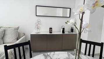 A modern room with a marble floor, a white sofa, a grey cabinet, and a large mirror.
