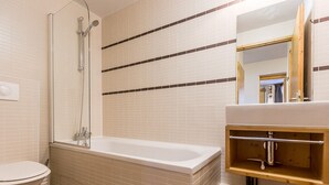 A bathroom with a bathtub, toilet, and a mirror above the sink. - Modern 4-room apartment, 2 terraces, covered parking, ski-in/ski-out (La Plagne Montchavin Les Coches)