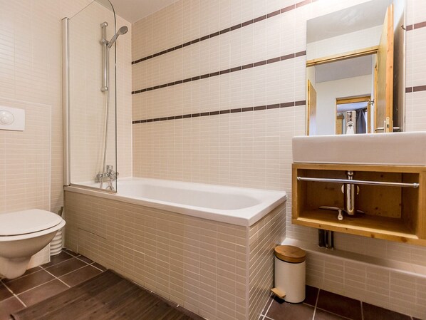 A bathroom with a bathtub, toilet, and a mirror above the sink.