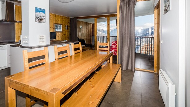 A modern kitchen with wooden accents, a dining area with a bench, and a view of mountains through large windows. - Modern 4-room apartment, 2 terraces, covered parking, ski-in/ski-out (La Plagne Montchavin Les Coches)