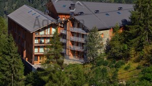 A multi-story wooden building with balconies, surrounded by dense forest. - Modern 4-room apartment, 2 terraces, covered parking, ski-in/ski-out (La Plagne Montchavin Les Coches)