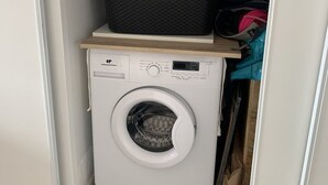 Een compacte wasmachine met een bedieningspaneel en een klein mandje bovenop.