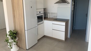 Een moderne keuken met witte kasten, een inbouwoven, een roestvrijstalen afzuigkap en een klein aanrecht.
