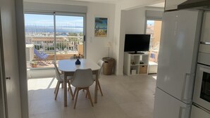 Een moderne keuken met een groot raam, een eethoek met een tafel en stoelen, en een televisie.