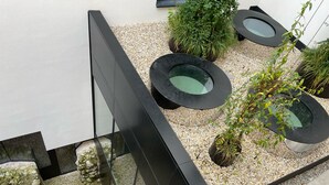 A modern outdoor area with a reflective water feature, surrounded by gravel and potted plants. - Platzhirsch Kufstein (Kufstein)