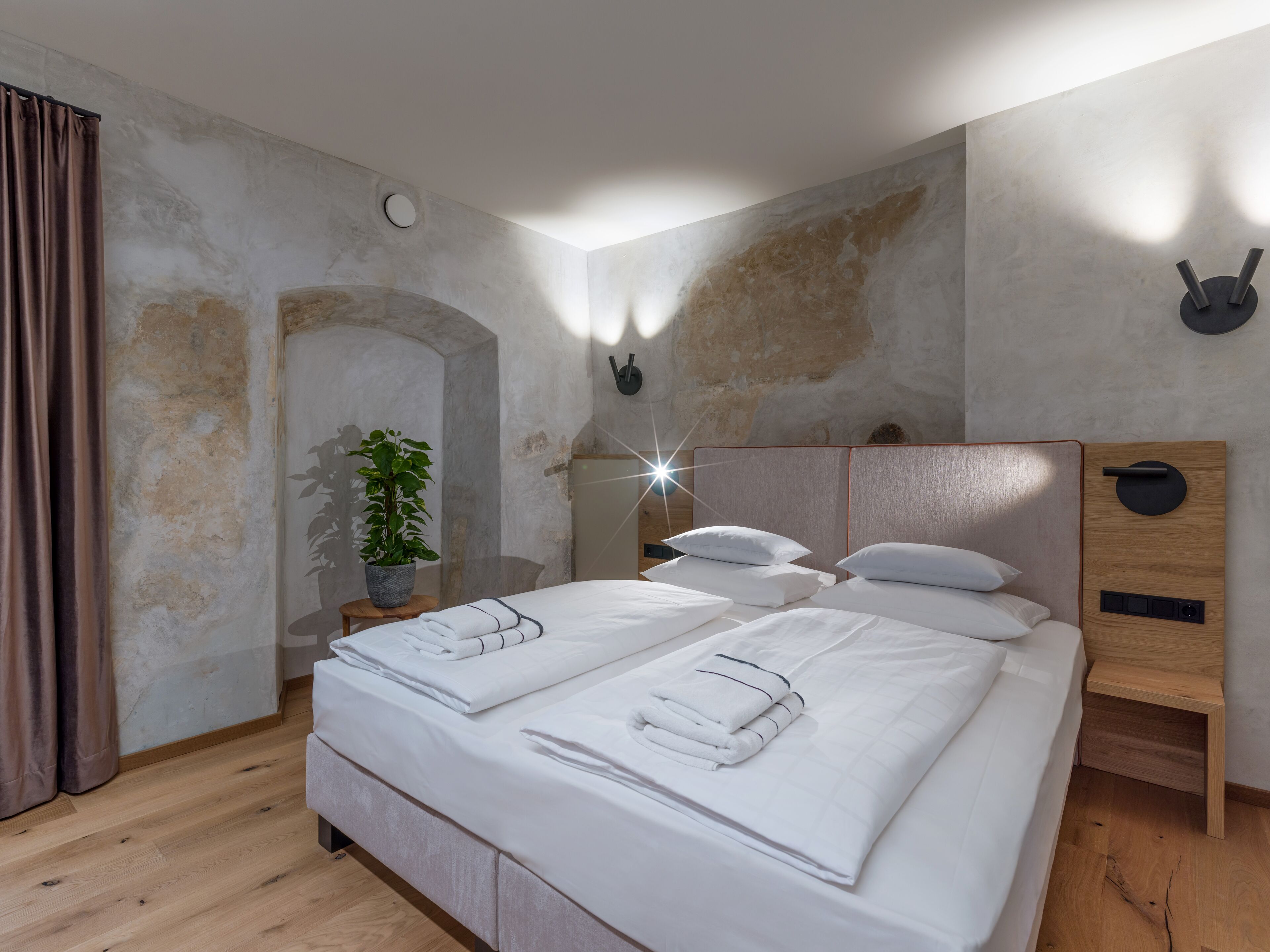 Ein modernes Schlafzimmer mit einem großen Bett, einem kleinen Tisch mit einer Pflanze und einem außergewöhnlichen Wanddesign.
