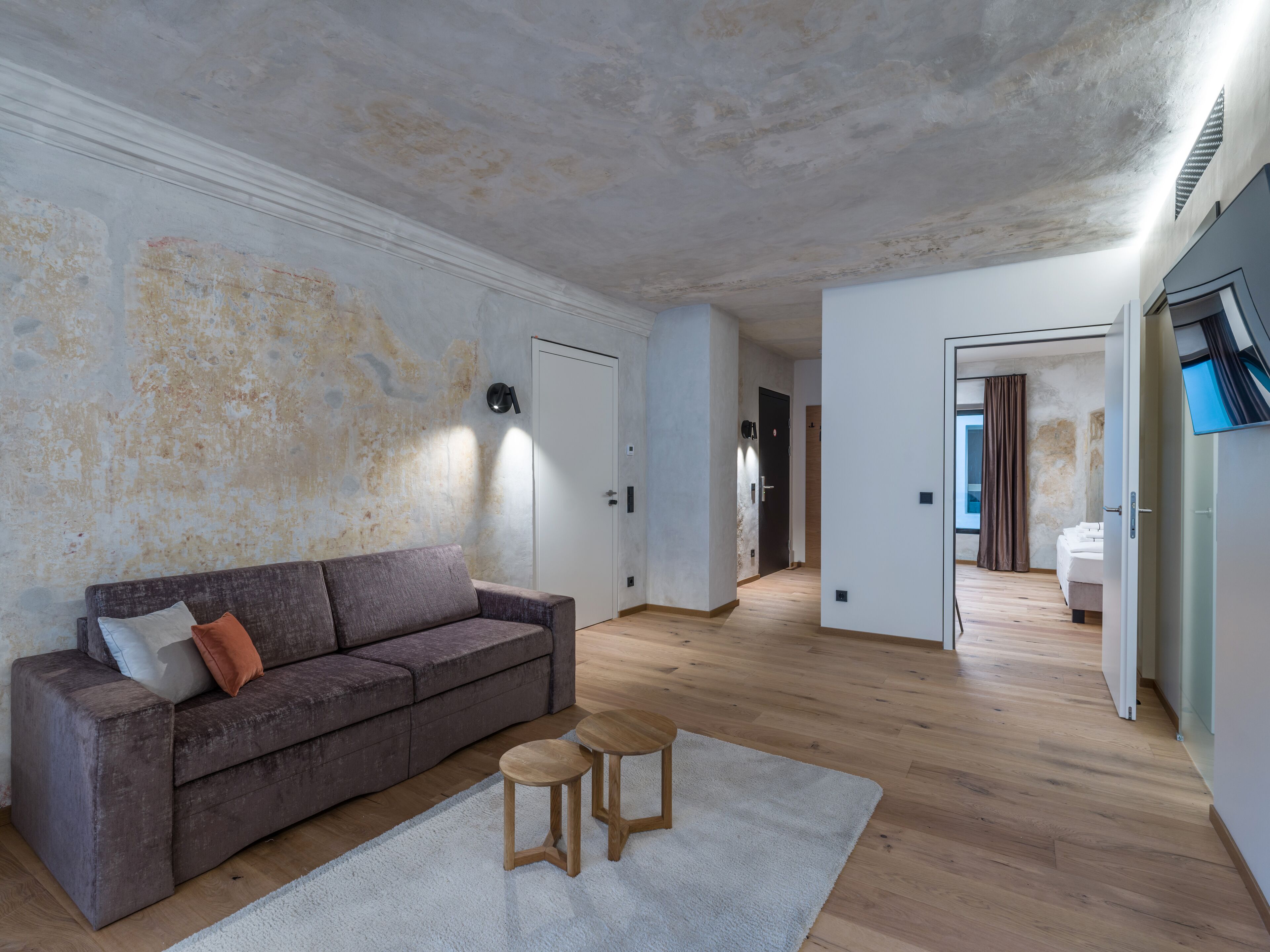 A spacious living area with a sofa, two stools, and a white rug.