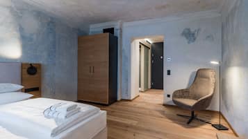 Un dormitorio con un armario de madera, una silla y una cama con ropa de cama blanca impecable.