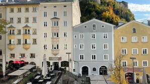 A historic building with a castle-like structure on a hill, surrounded by modern buildings with outdoor seating areas. - Platzhirsch Kufstein (Kufstein)
