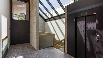 A modern elevator with a glass ceiling, a wooden bench, and a door with a handle.