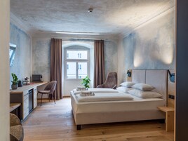 Un dormitorio con cama, escritorio, silla y ventana con cortinas.