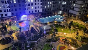 A nighttime view of a residential complex with multiple swimming pools, a basketball court, and landscaped gardens. - Bcons Garden Luxury Apartment (Ho Chi Minh City)