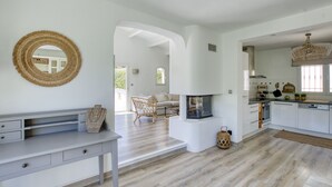 Cuina àmplia amb una illa central, armaris blancs i un mirall gran a la paret.