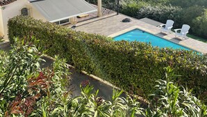 Una casa amb teulada d'àmples rajoles, piscina i vistes a un turó forestal.